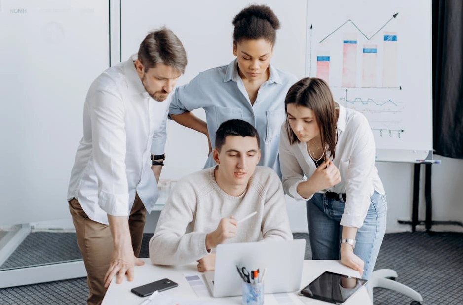 A team of professionals collaborating around a whiteboard covered in flowcharts and financial diagrams.